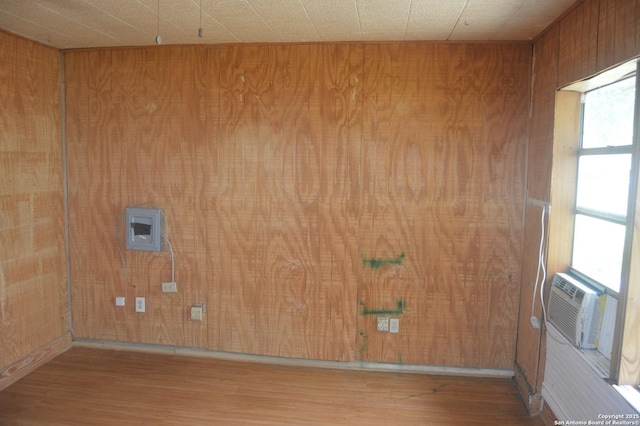 laundry area featuring cooling unit, wood walls, and wood finished floors