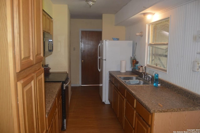 kitchen featuring freestanding refrigerator, a sink, black microwave, stainless steel range with electric cooktop, and wood finished floors