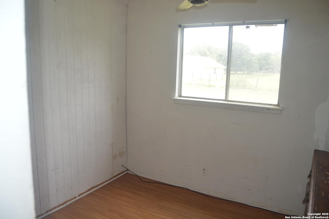 spare room with wood walls, ceiling fan, and wood finished floors