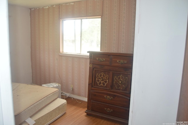 bedroom featuring wallpapered walls, light wood-type flooring, and baseboards