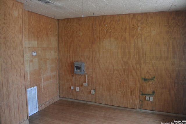 clothes washing area with wood walls, visible vents, and wood finished floors