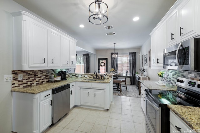 190 Da Vinci, San Antonio, TX 78258 - kitchen with stainless steel appliances, a chandelier, a sink, decorative backsplash, and a peninsula