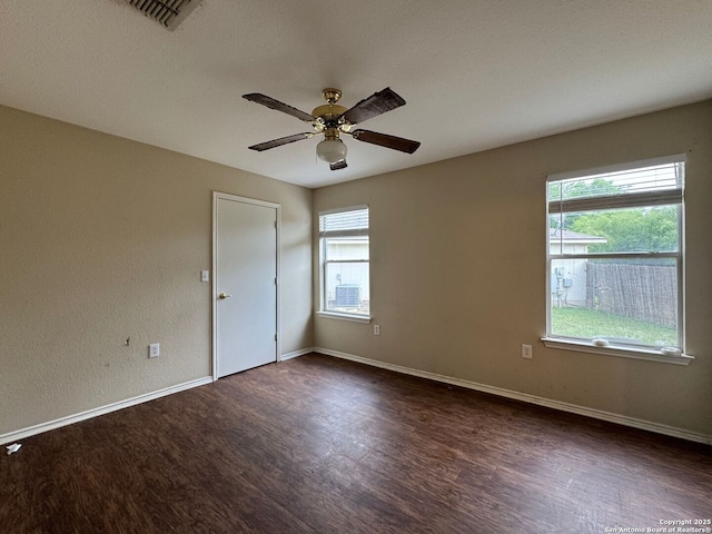 empty room with dark wood-type flooring, baseboards, visible vents, and ceiling fan