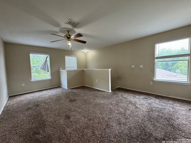 empty room featuring a ceiling fan, a wealth of natural light, baseboards, and visible vents