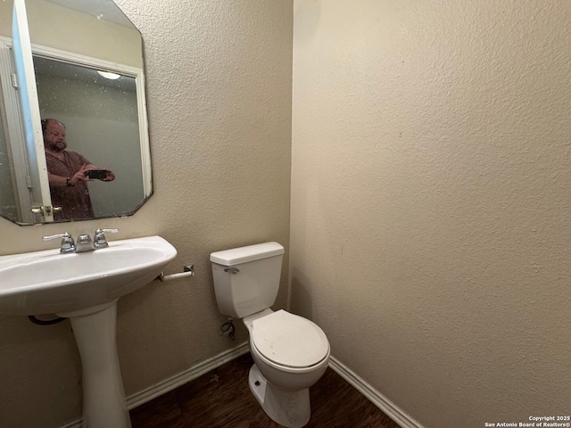 bathroom with toilet, baseboards, and wood finished floors