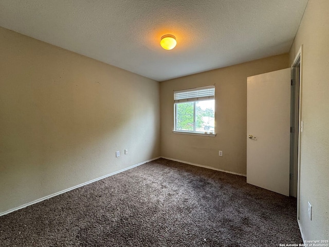 empty room with carpet flooring, a textured ceiling, and baseboards