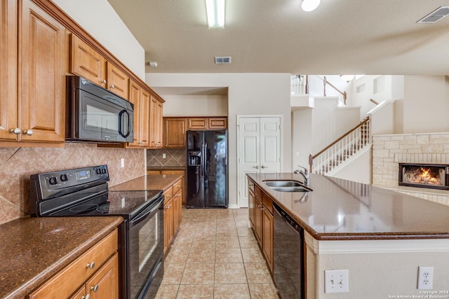 10603 Catfish Ln, San Antonio, TX 78224 - kitchen with black appliances, a sink, decorative backsplash, a center island with sink, and brown cabinets