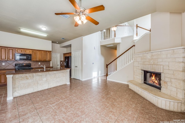 10603 Catfish Ln, San Antonio, TX 78224 - kitchen featuring black appliances, brown cabinets, ceiling fan, backsplash, and a high ceiling