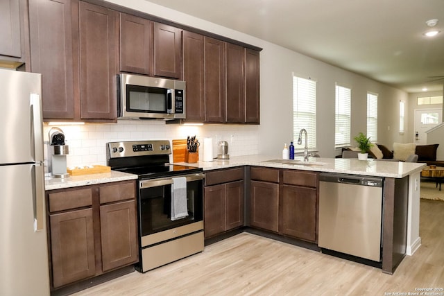 236/238 Joseph Cir, Cibolo, TX 78108 - kitchen with a peninsula, light wood-style flooring, a sink, stainless steel appliances, and tasteful backsplash