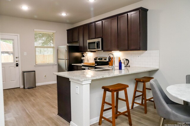 236/238 Joseph Cir, Cibolo, TX 78108 - kitchen with a sink, stainless steel appliances, light wood-type flooring, dark brown cabinetry, and decorative backsplash