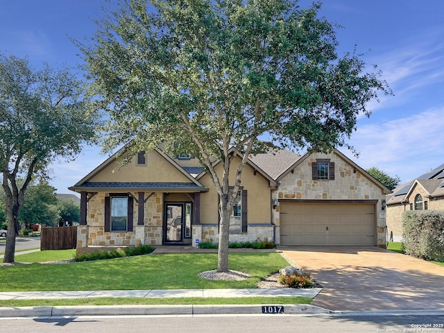 craftsman house featuring stone siding, an attached garage, fence, a front yard, and driveway