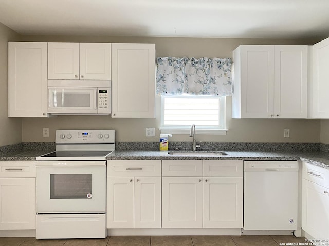 kitchen featuring a sink, white appliances, dark countertops, and white cabinets