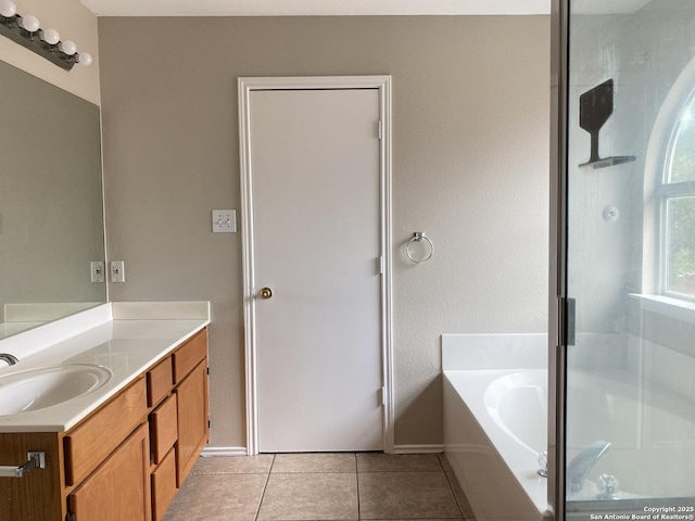 bathroom featuring baseboards, a shower stall, tile patterned flooring, a garden tub, and vanity