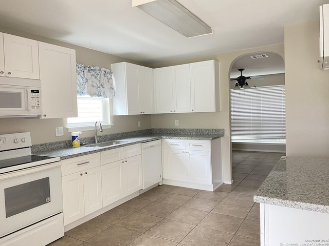 kitchen with light stone countertops, light tile patterned floors, white appliances, a sink, and white cabinetry
