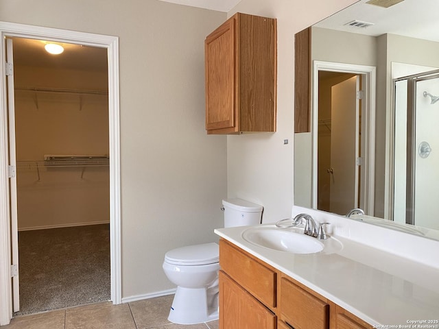 bathroom with toilet, vanity, visible vents, tile patterned flooring, and a shower stall