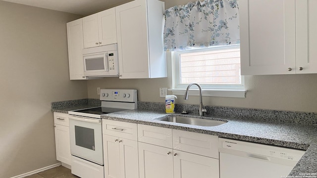 kitchen with white cabinetry, a sink, and white appliances