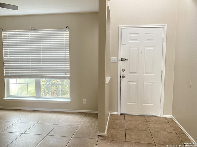 tiled foyer entrance with baseboards and ceiling fan