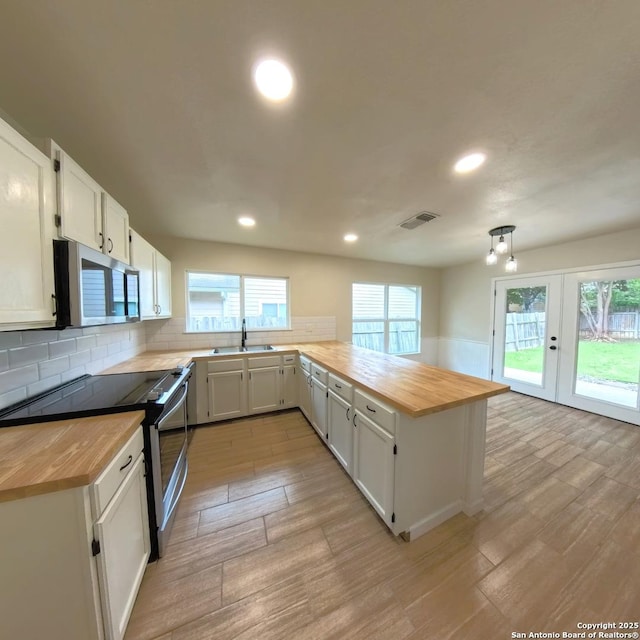 13243 Larkfield, San Antonio, TX 78233 - kitchen with a sink, a peninsula, appliances with stainless steel finishes, butcher block counters, and light wood-style floors