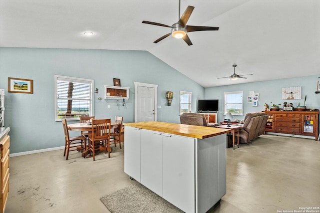 kitchen with a ceiling fan, butcher block countertops, finished concrete flooring, a healthy amount of sunlight, and white cabinets