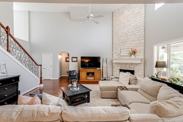 living room with wood finished floors, stairway, a towering ceiling, ceiling fan, and arched walkways