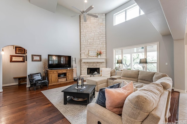living area featuring high vaulted ceiling, a fireplace, baseboards, arched walkways, and ceiling fan