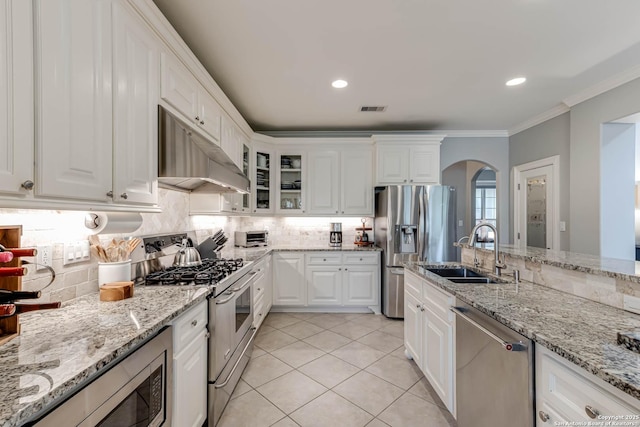 kitchen with under cabinet range hood, visible vents, a sink, arched walkways, and appliances with stainless steel finishes