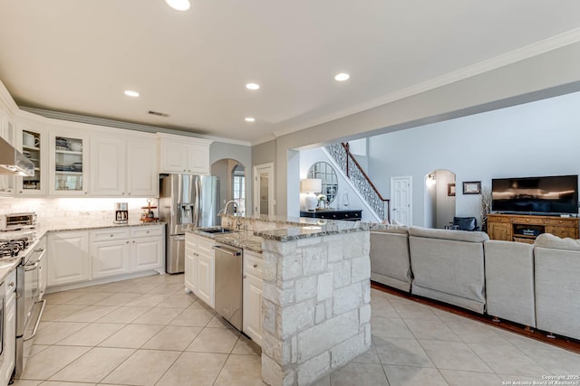 kitchen featuring arched walkways, open floor plan, appliances with stainless steel finishes, and a sink