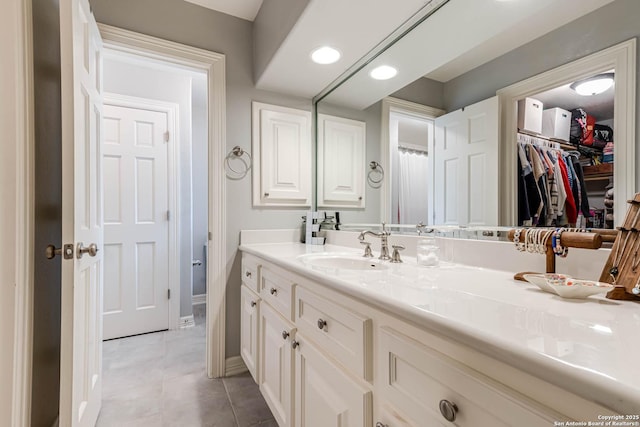 full bath featuring baseboards, tile patterned flooring, vanity, a spacious closet, and recessed lighting