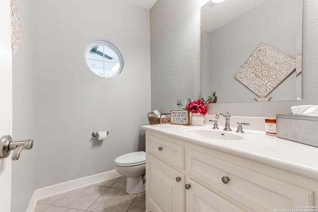half bath with toilet, tile patterned flooring, vanity, and baseboards
