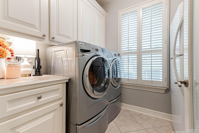 clothes washing area with baseboards, light tile patterned floors, cabinet space, and washer and clothes dryer