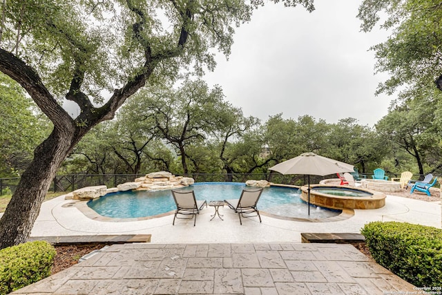 view of swimming pool with a patio area, a pool with connected hot tub, and fence