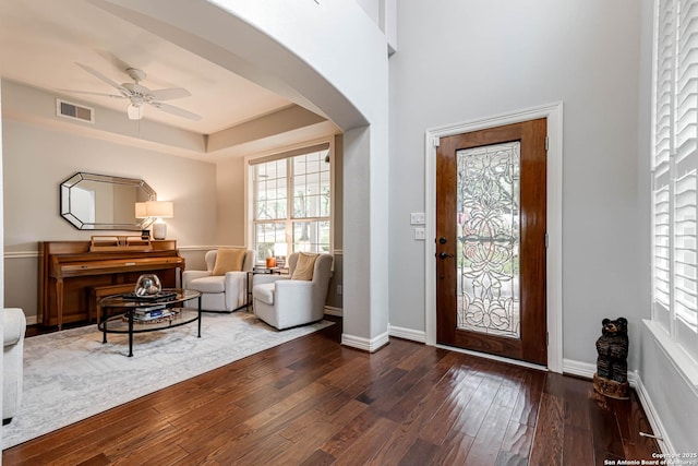 foyer with visible vents, ceiling fan, arched walkways, dark wood-style floors, and baseboards