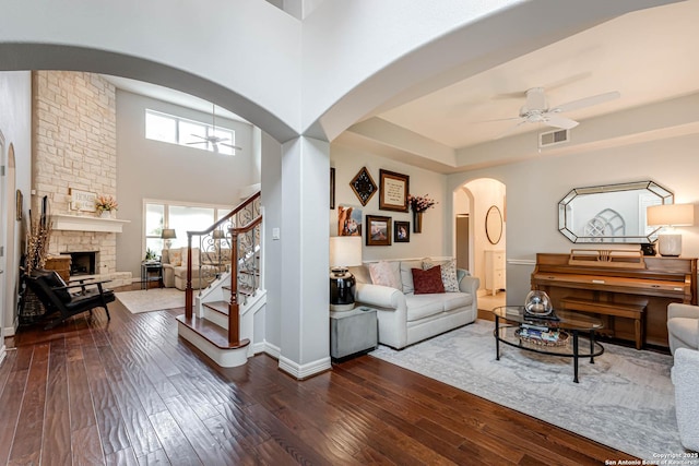living area with arched walkways, a ceiling fan, visible vents, and dark wood finished floors