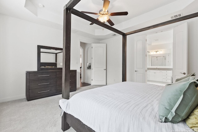 bedroom featuring light carpet, baseboards, ensuite bathroom, and a ceiling fan