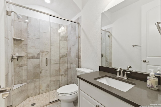 bathroom featuring a stall shower, toilet, and vanity