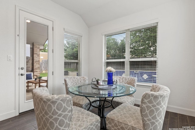 dining space with dark wood-style flooring, lofted ceiling, and baseboards