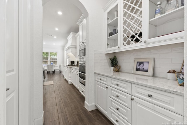 bar area featuring arched walkways, backsplash, dark wood finished floors, recessed lighting, and wall oven