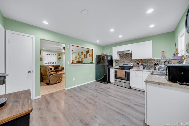 5118 War Cloud, San Antonio, TX 78242 - kitchen with black appliances, under cabinet range hood, white cabinetry, light wood-style flooring, and tasteful backsplash