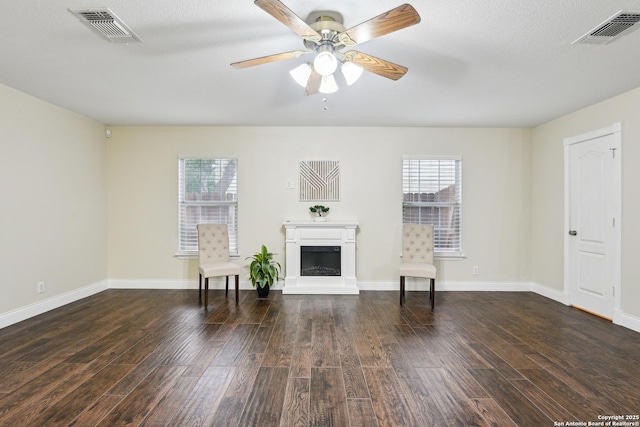 living room with wood finished floors, a ceiling fan, and a fireplace with raised hearth