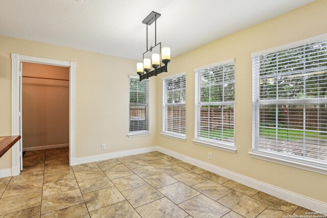 unfurnished dining area featuring baseboards and a chandelier