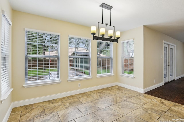 unfurnished dining area featuring a chandelier and baseboards