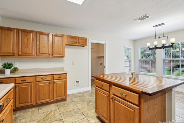 kitchen featuring brown cabinets, light countertops, hanging light fixtures, and a chandelier