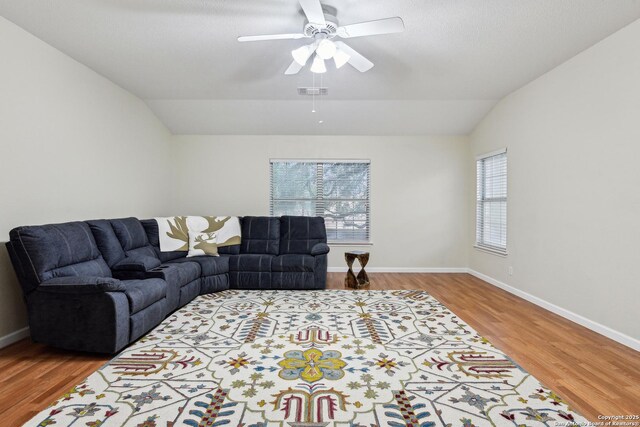 living area featuring vaulted ceiling, wood finished floors, ceiling fan, and baseboards