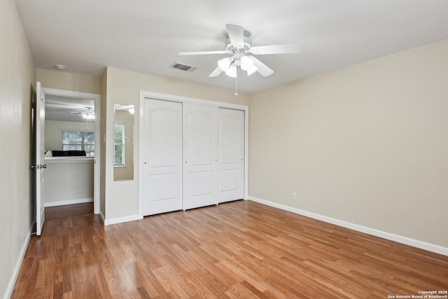 unfurnished bedroom with light wood-type flooring, baseboards, a closet, and ceiling fan