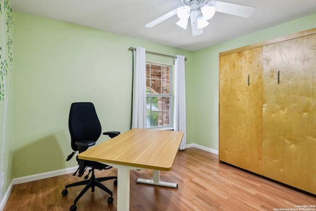 office area with baseboards, light wood-style floors, and ceiling fan
