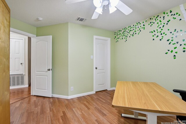 unfurnished office featuring light wood-type flooring, baseboards, and ceiling fan