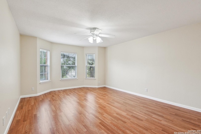empty room featuring light wood-style floors, ceiling fan, baseboards, and a textured ceiling
