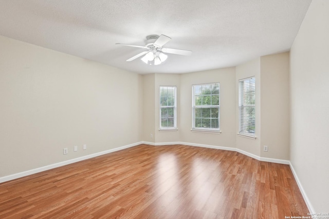 unfurnished room featuring light wood-style flooring, baseboards, ceiling fan, and a textured ceiling