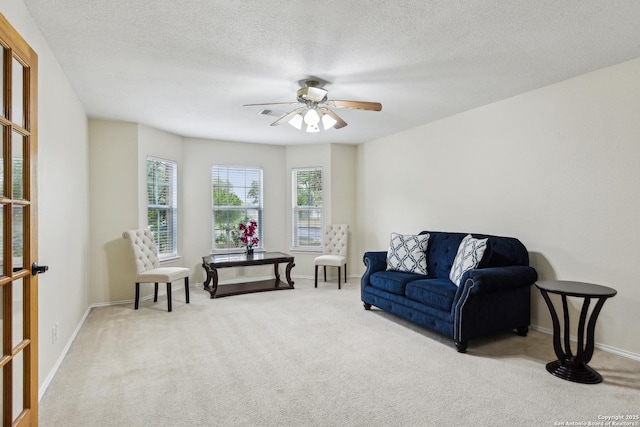 living area featuring carpet flooring, a ceiling fan, baseboards, and a textured ceiling