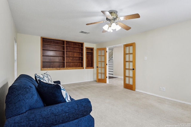 living area featuring carpet flooring, french doors, a ceiling fan, baseboards, and stairway